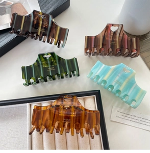 Detail of five large heart-shaped acetate hair claws in various elegant striped colors