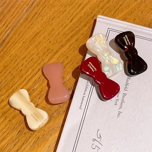 Elegant bow-shaped acetate hair clips in five assorted colors displayed on a book
