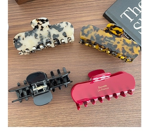 Selection of elegant acetate claw clips in tortoiseshell and solid colors on a wood surface