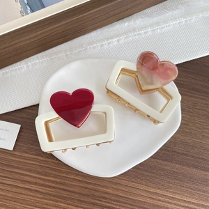 Elegant 6cm heart-shaped hair claw clips in red and pink marble on a white ceramic tray