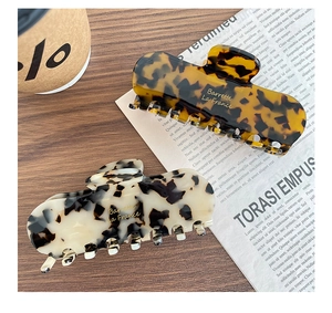 Detail of square acetate hair claws with leopard and marble textures on a wooden table