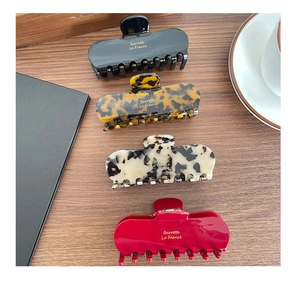 Macro view of four elegant acetate hair claws in tortoise and solid colors on wooden desk