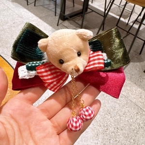 Detail of Christmas bear hair accessory featuring green velvet bow and plaid plush balls