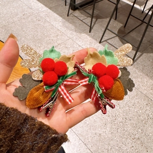 Detail view of a Christmas hair clip featuring glittery reindeer antlers and berries