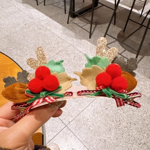 Detailed view of Christmas hair clips with glitter reindeer antlers and red pom-poms