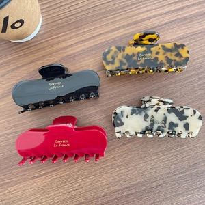 Set of four premium acetate claw clips in leopard, marble, and solid colors on wood background
