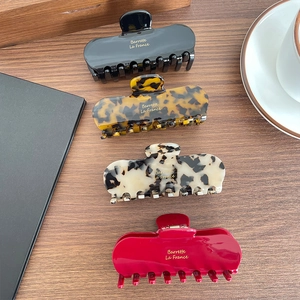 Set of four tortoiseshell and solid color acetate hair claws on a wooden table