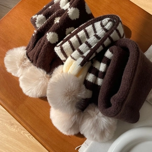 Détail d'une écharpe d'hiver en tricot à pois marron avec pompons en fausse fourrure