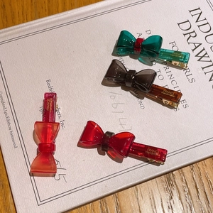 Set of four handmade acetate bow hair clips in green, amber, red, and orange tones
