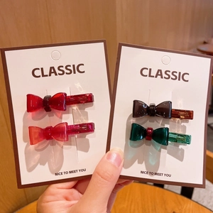 Handmade acetate bow hair clips in multiple colors displayed on a classic white card