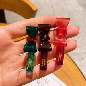 Macro shot of small acetate bow hair clips in translucent green, brown, and red colors