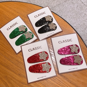 Lot de quatre paires de barrettes étoilées pailletées pour filles sur fond de bois