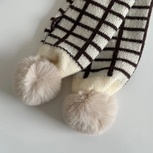 Détail d'écharpe en tricot à motif quadrillé marron et pompons en fourrure pour enfants
