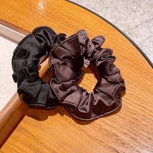 Close-up of dual-color elastic satin hair scrunchies in black and coffee brown colors