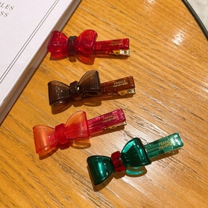 Set of four translucent acetate bow hair clips in vibrant jelly colors on a wooden surface