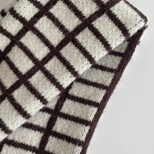 Gros plan détaillé sur le motif tricoté à carreaux marron et beige d'une écharpe