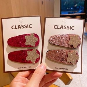 Gros plan de barrettes à cheveux pailletées en forme d'étoile rose et bronze sur carte