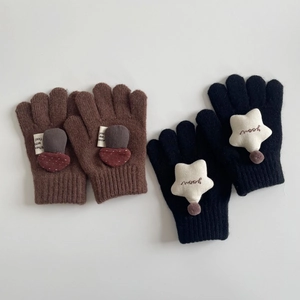 Detail of knitted gloves with mushroom and star patches showing ribbed cuffs and texture