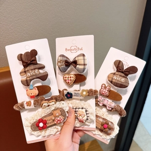 Close-up of brown plaid bow hair clips and plush bear hair ties for girls
