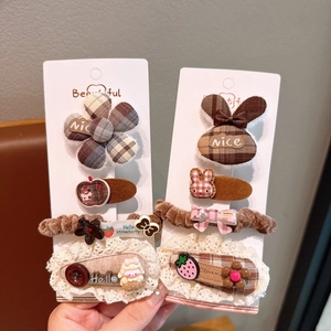 Close-up of plaid bow hair clips and scrunchies in brown and beige colors