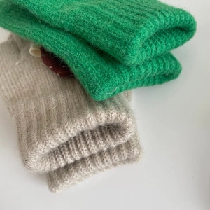 Detailed macro view showing the soft rib-knit texture of children's wool gloves in green