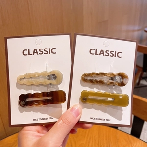 Détail des barrettes à cheveux ondulées en résine colorée avec finition laquée