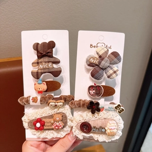 Detail of plaid cotton bow hairpins and cute bear hair ties for girls in brown tones