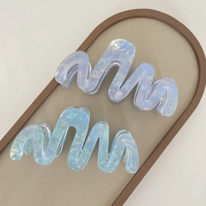 Detail view of large wavy acetate hair claws in pastel purple and blue pearlescent finish