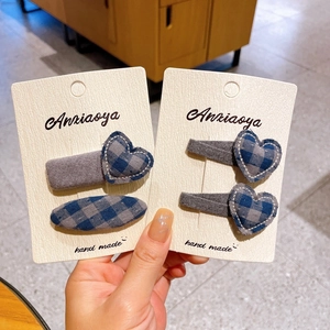 Detailed view of handmade grey-blue plaid heart and oval hair clips on beige display cards