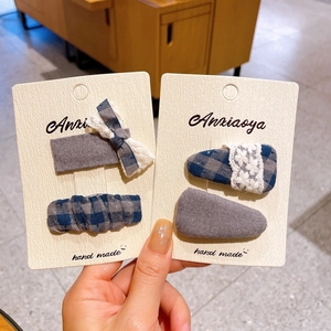 Close-up of handmade grey-blue plaid and lace hair clips set on a branded card