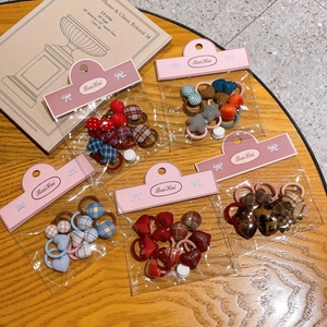 Detail view of colorful plaid and heart hair ties in individual packaging on a wooden table