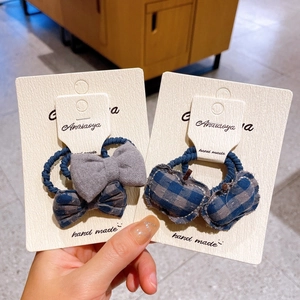 Detail of blue-grey plaid bow and heart-shaped fabric hair ties on white display cards