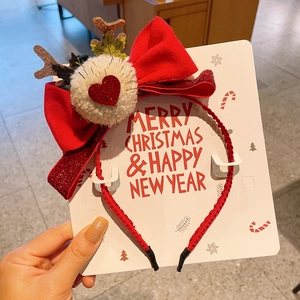 Detail of red velvet bow headband with reindeer antlers and plush pompom for Christmas