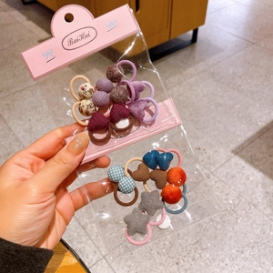 Detail of colorful fabric flower and heart hair ties set in clear plastic packaging