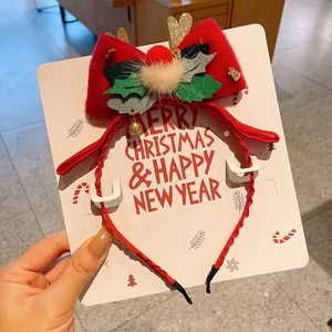 Detail of Christmas headband with red bow, glitter reindeer antlers and holly leaves