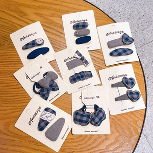 Detailed set of blue checkered bow hair clips and scrunchies on a wooden table