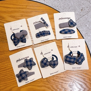 Grey-blue plaid hair clip and tie set with heart, star, and bow shapes on display card