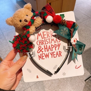Detail of Christmas headband with plush bear, Santa figure and bow on card packaging