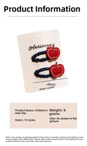 Détail des barrettes à cheveux brodées en forme de pomme rouge sur carte blanche