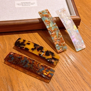 Detailed set of four tortoiseshell acetate spring hair clips on a wooden display