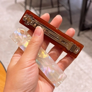 Detail of tortoise shell and pearlescent resin ponytail clip with metal spring back