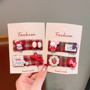 Nahaufnahme der Vintage-Haarspangen aus rotem Karostoff mit Cartoon-Hase und Blumenstickerei