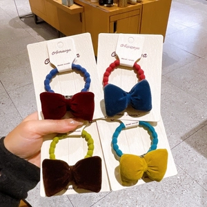 Detail view of velvet bow hair ties in burgundy, blue, brown, and yellow colors