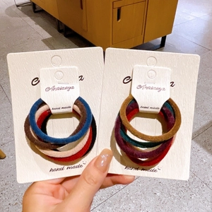 Detail showing two sets of high-elasticity braided hair ties in assorted earth tone colors