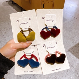 Detailed view of four colorful velvet heart-shaped scrunchies with handmade labels