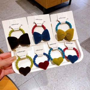 Close-up of seven velvet bow and heart scrunchies in rich autumn colors on a tray