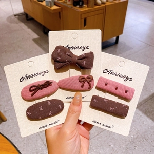 Détail de barrettes à cheveux en tissu avec motifs floraux et perles sur support carton