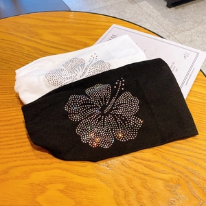 Detail of wide cotton headbands in black and white with rhinestone hibiscus floral patterns