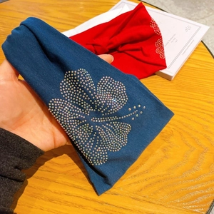 Close-up of stretchy wide fabric headband showing hibiscus patterns and sparkling rhinestones