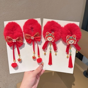 Detail van rode pluche haaraccessoires met leeuwenborduurwerk en kwastjes voor meisjes